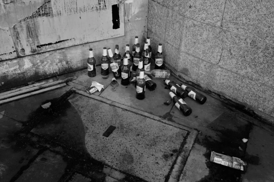 19 beer bottles left in the corner between 2 buildings