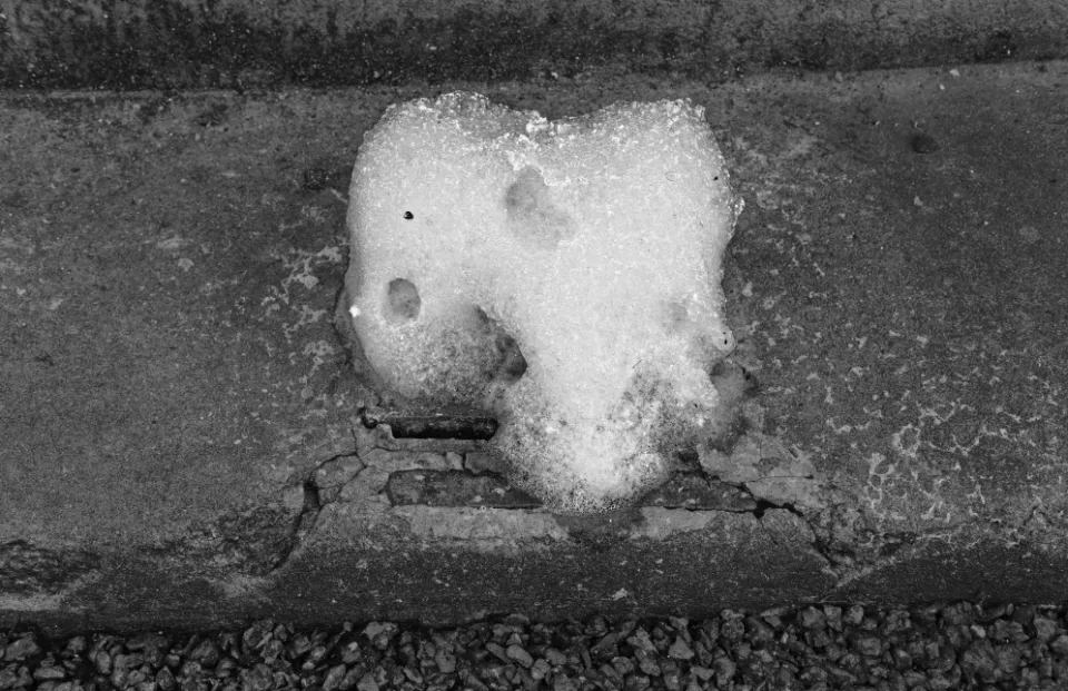 Close up of foam escaping from a drain cover on the kerb