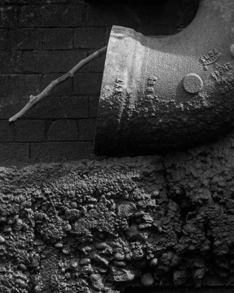 Close up of bare stick poking from an encrusted pipe end on the Thames shore