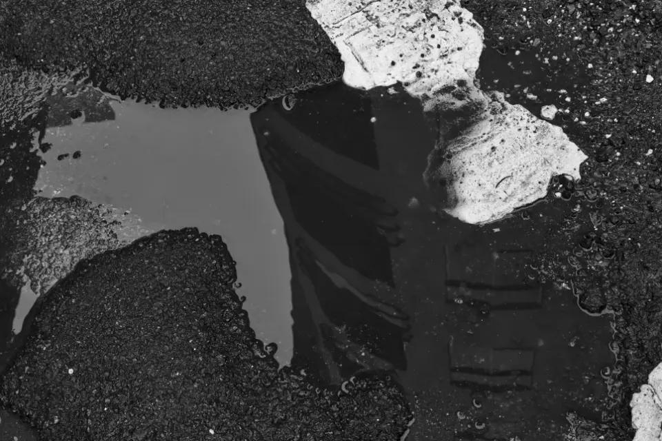 Close up showing reflection of office building in a puddle in a rutted road