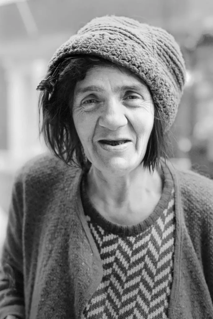 Half-length photo of a homeless woman in Soho smiling at the camera